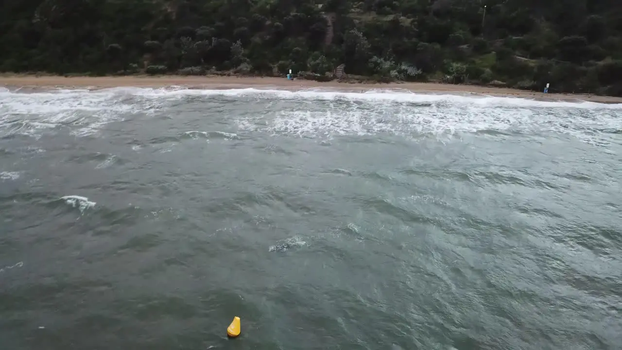 Drone aerial over ocean Melbourne wavy windy cloudy man swimming on beach