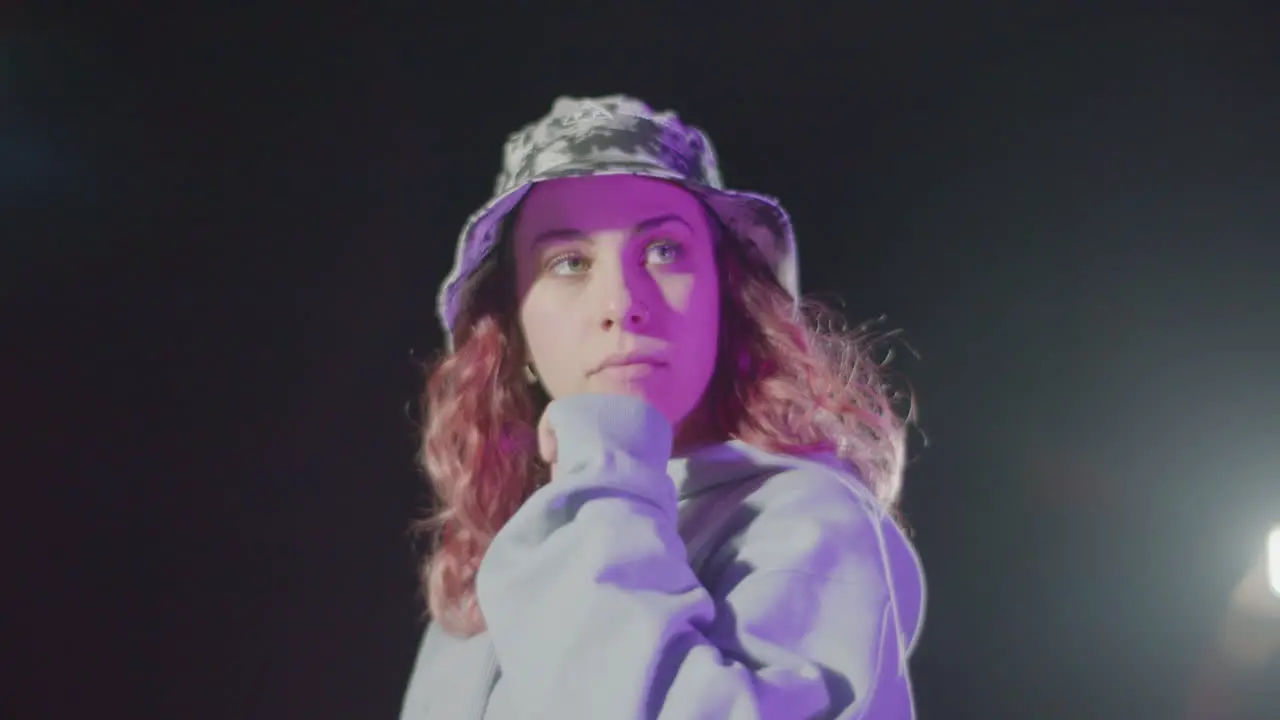 Attractive Young Woman In Hat Posing In Street At Night