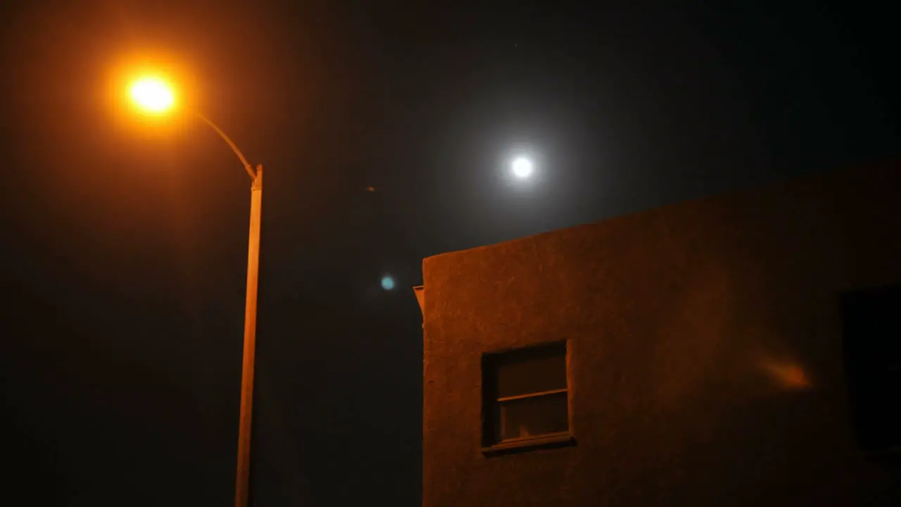 Time lapse of moon rising over a house and street lamp