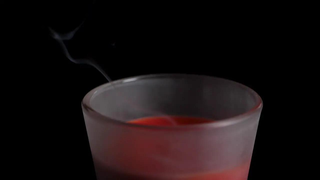 Smoke rising up from a red candle which got blowed out