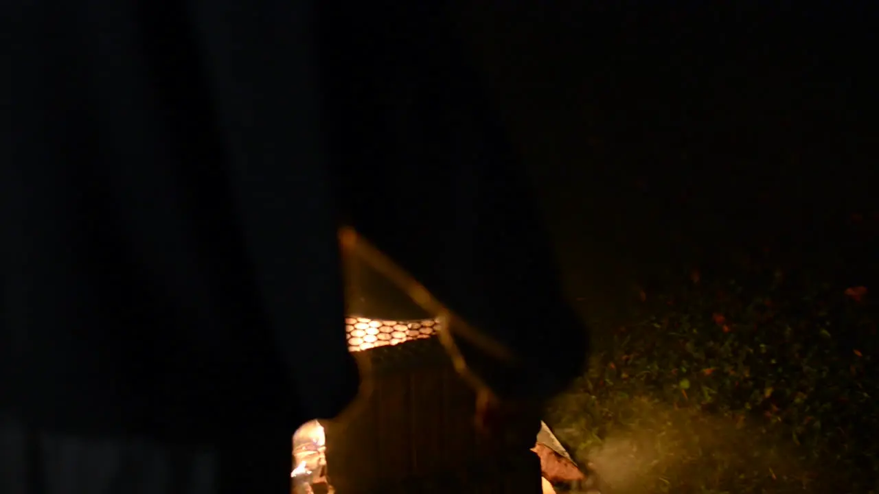 Man placing food on a pan over a fire pit