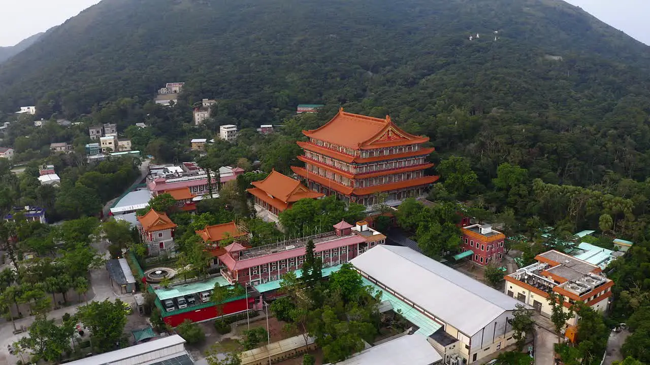 drone shot of a big Chinese Buddhist temple in a little village with a forest and a mountain around during the day