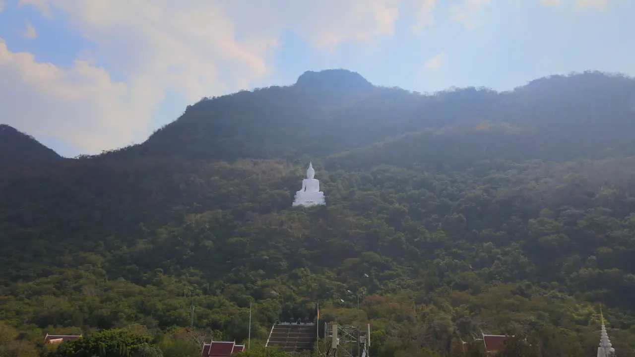 Luang Por Khao Wat Theppitak Punnaram a reverse aerial footage of the famus white temple on the mountain revealing a communication antenna and stairway up shrine and partly the complex