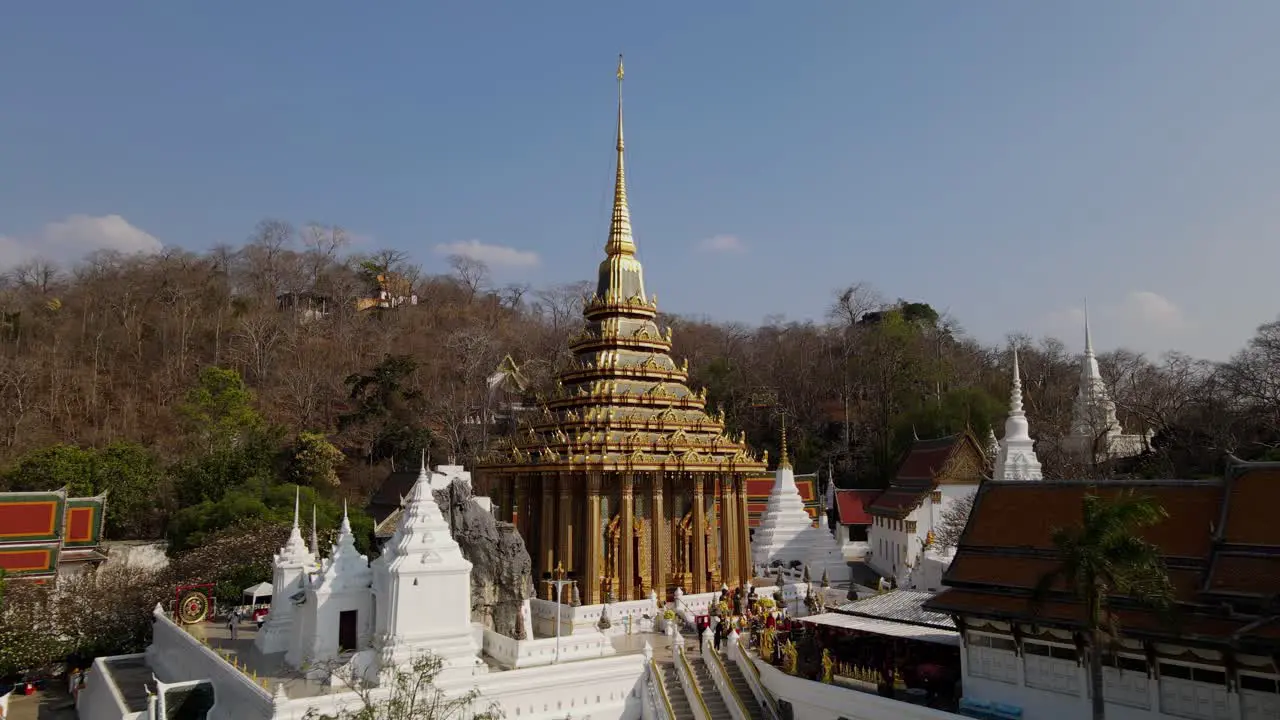 Wat Phra Phutthabat Saraburi Thailand an eye level aerial shot towards the stairs going up the temple and brown dying trees at the background people have come to pray and seek blessings