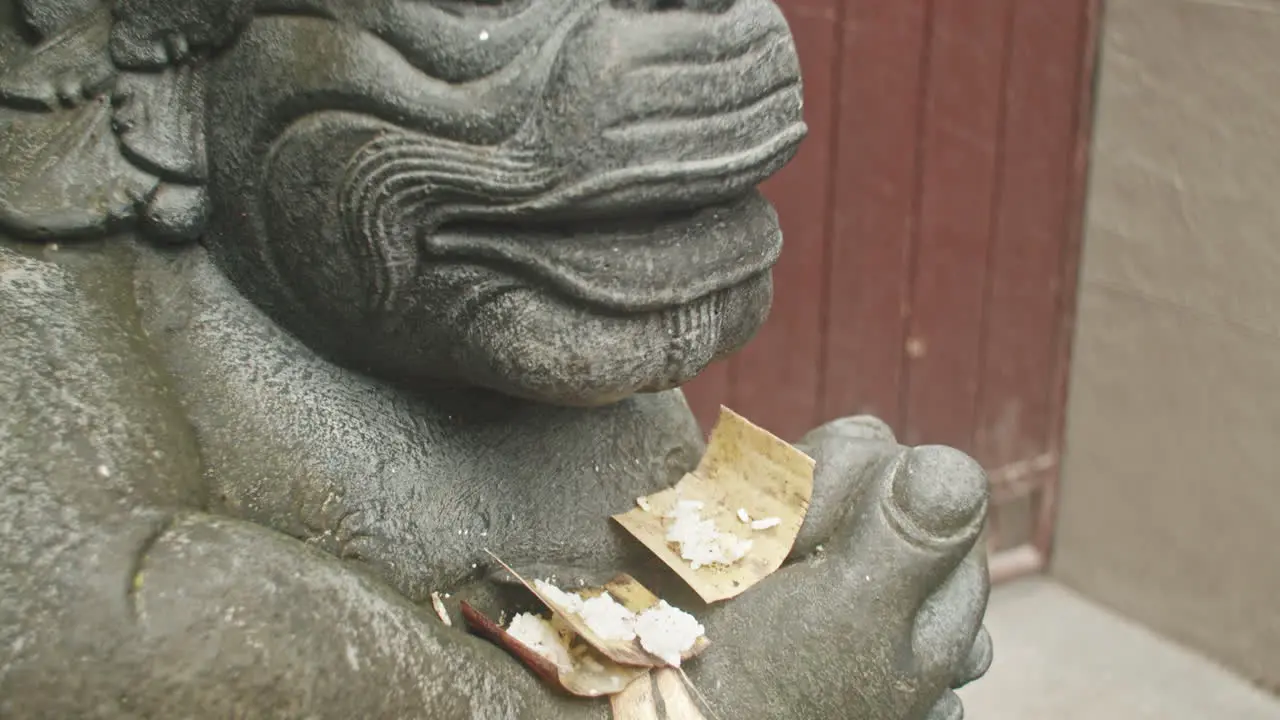 Detailed close up of hindu statue decorated with offerings panning up revealing face in Ubud in Bali Indonesia