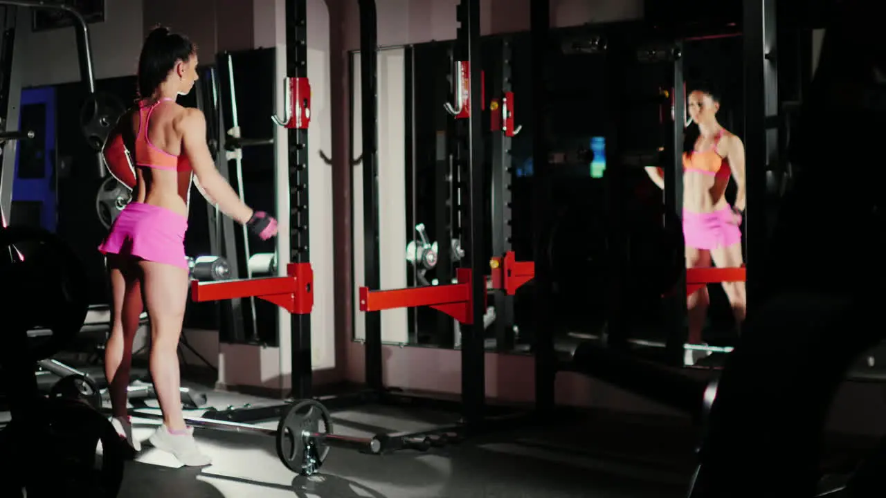 Athletic Woman A Professional Bodybuilder Posing In Front Of A Mirror Shows Muscles