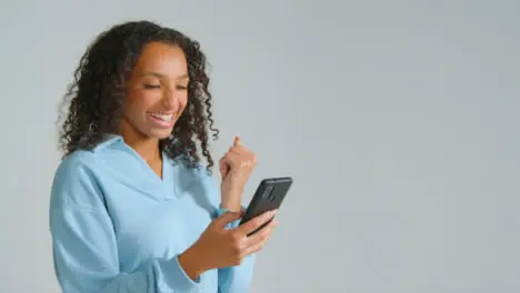 Portrait Shot of Young Adult Woman Smiling at Her Smartphone