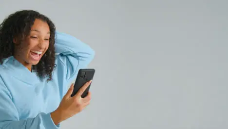 Portrait Shot of Young Adult Woman Celebrating with Smartphone 03