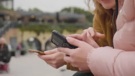 Close Up of Two Women Sitting Outside Using Their Phones