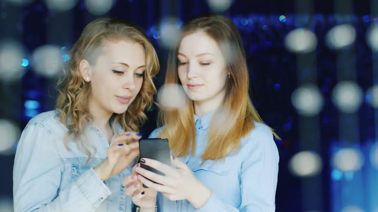 Two Young Women Use A Smartphone And Have A Good Time 1