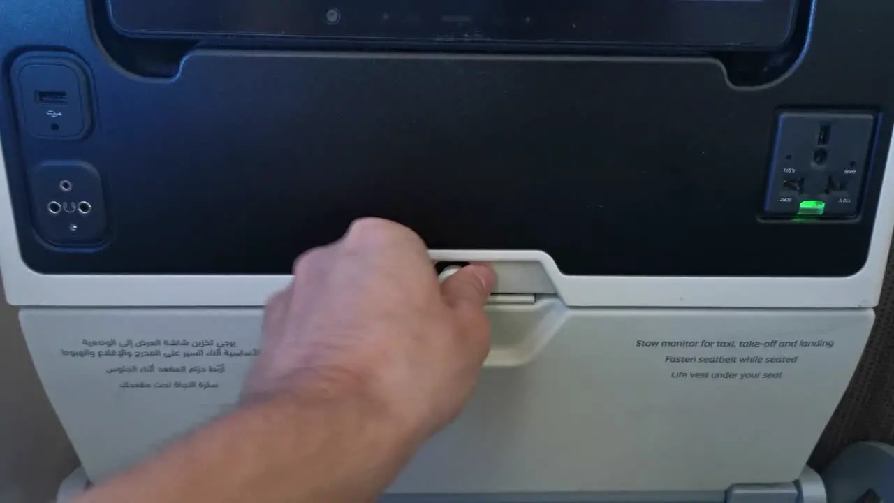 POV folding down a tray table on a plane one handed