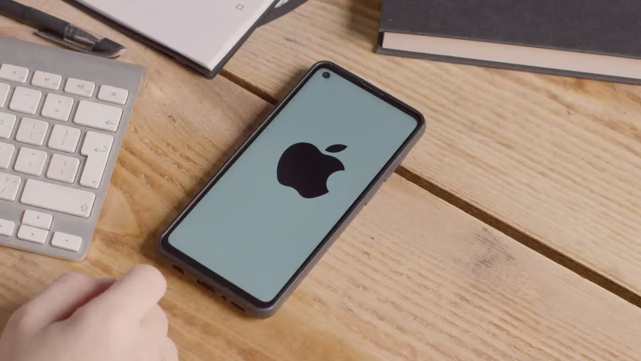 Mobile Phone On Desk With Screen Showing Brand Logos For Apple Google McDonalds Microsoft Tesla Verizon And Visa