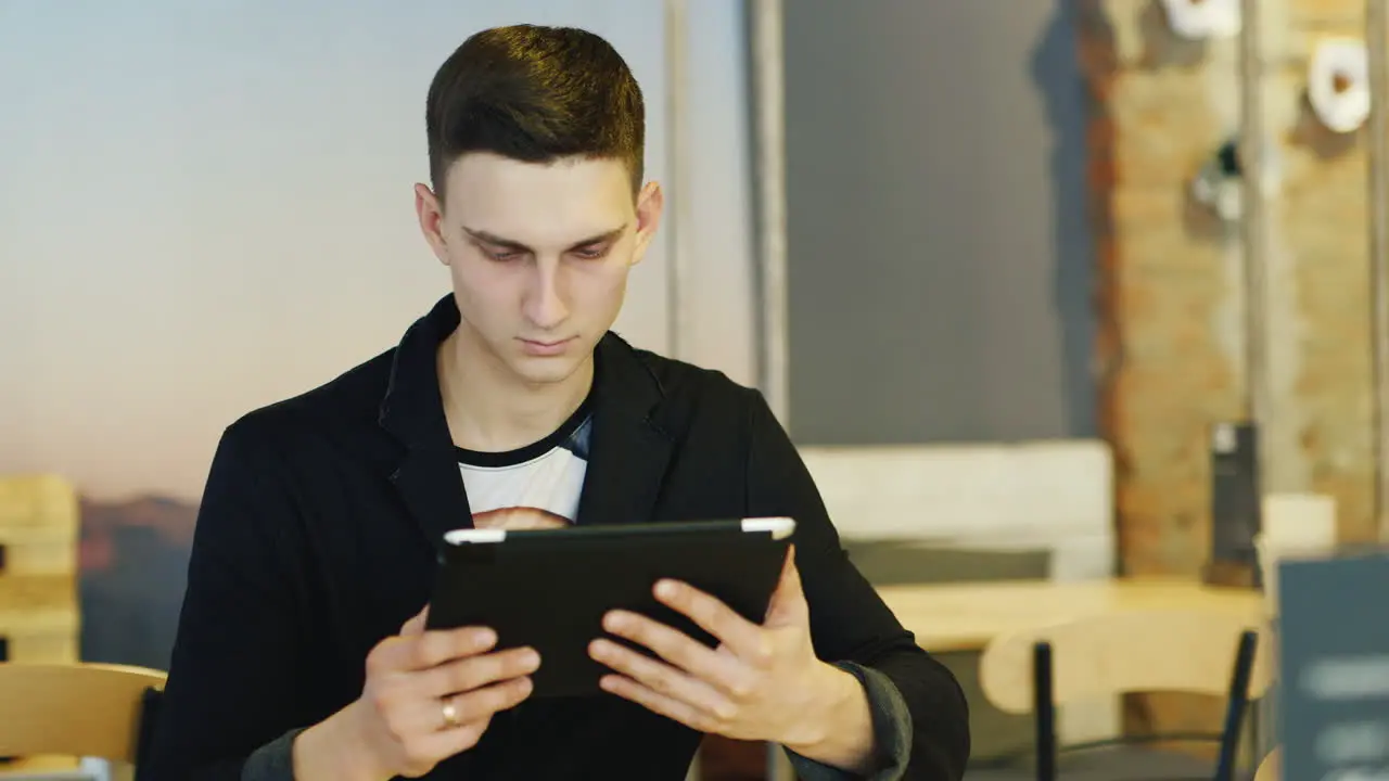 Stylish Man In A Suit Uses A Tablet In Cafe