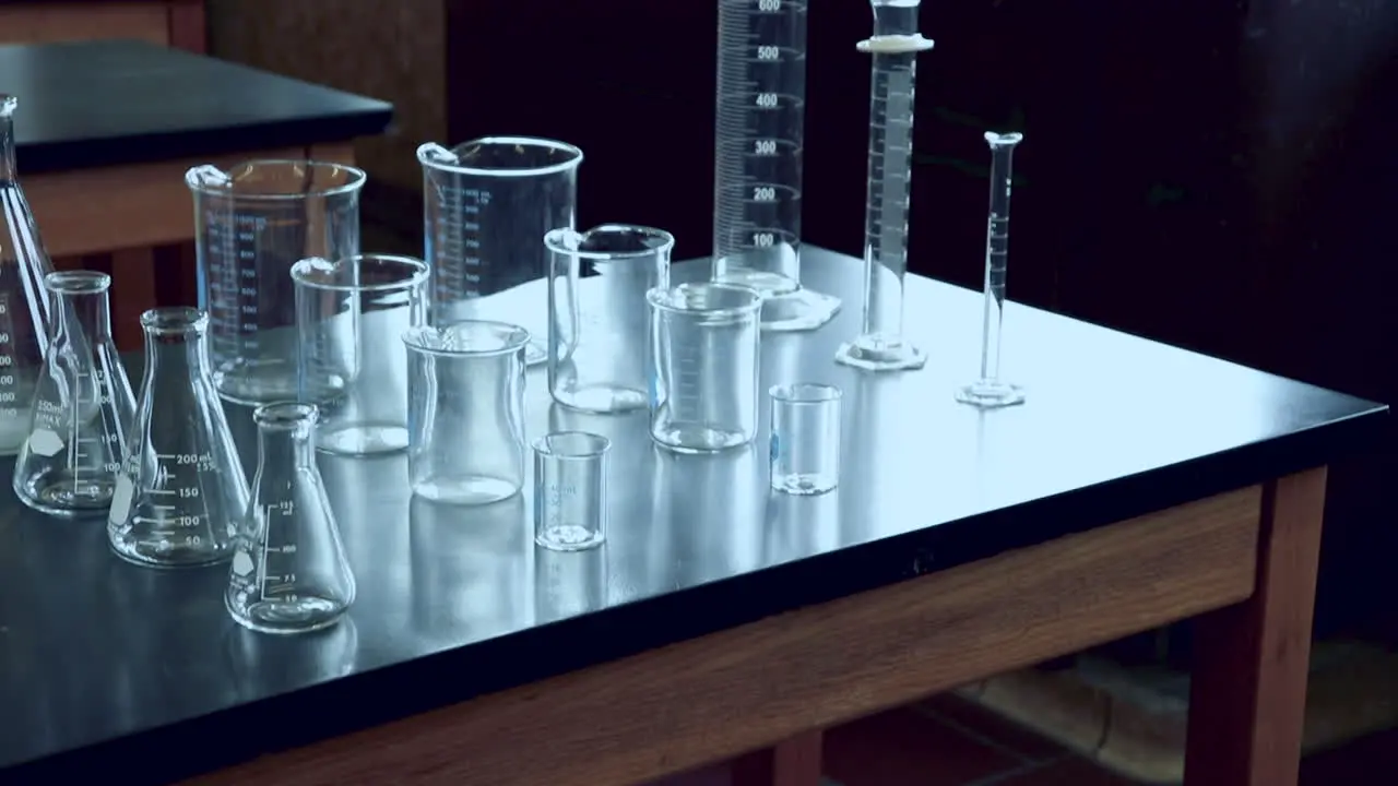 Tilting up to reveal black lab bench with a variety of chemical glassware in high school chemistry lab