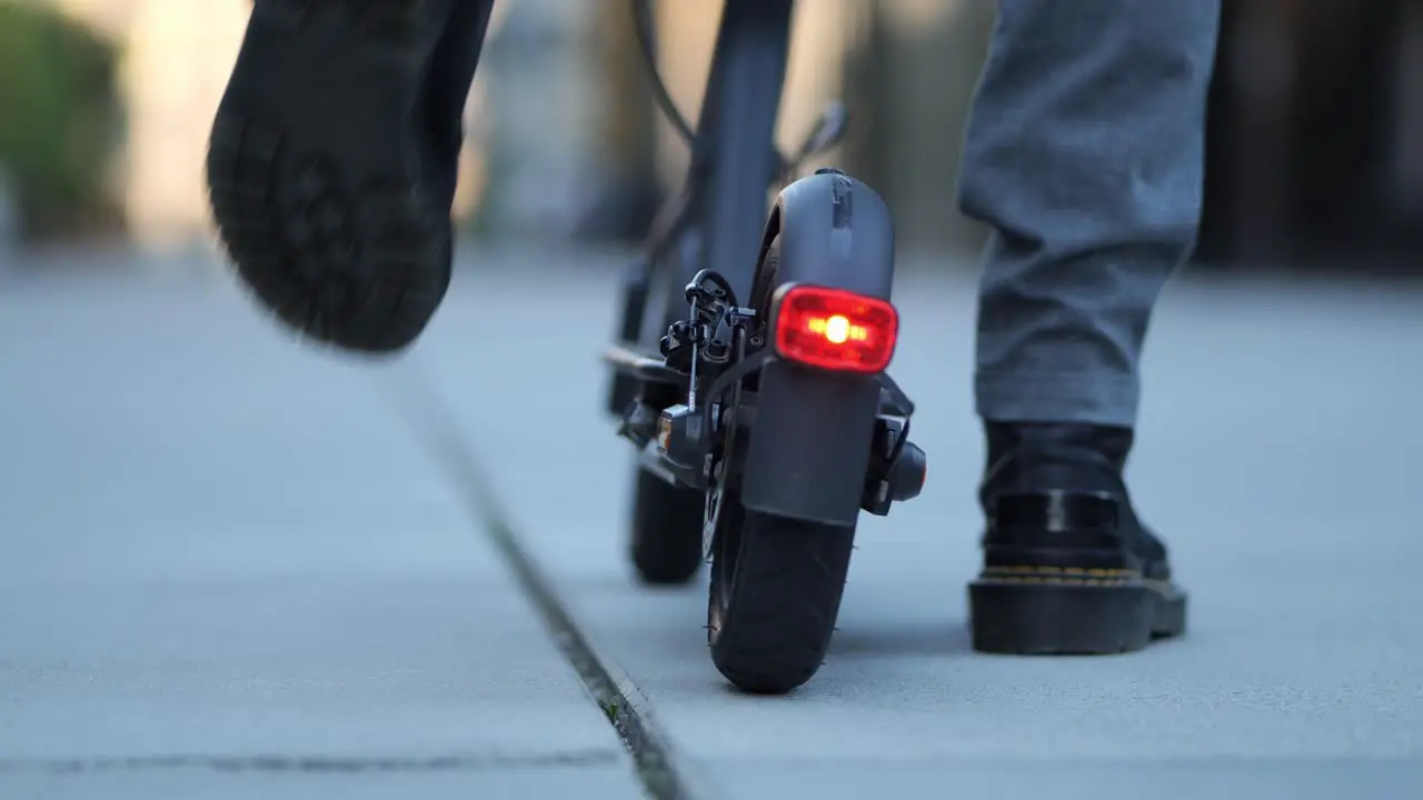 close up shot of the backlight of an e scooter while someone gets on and drives off