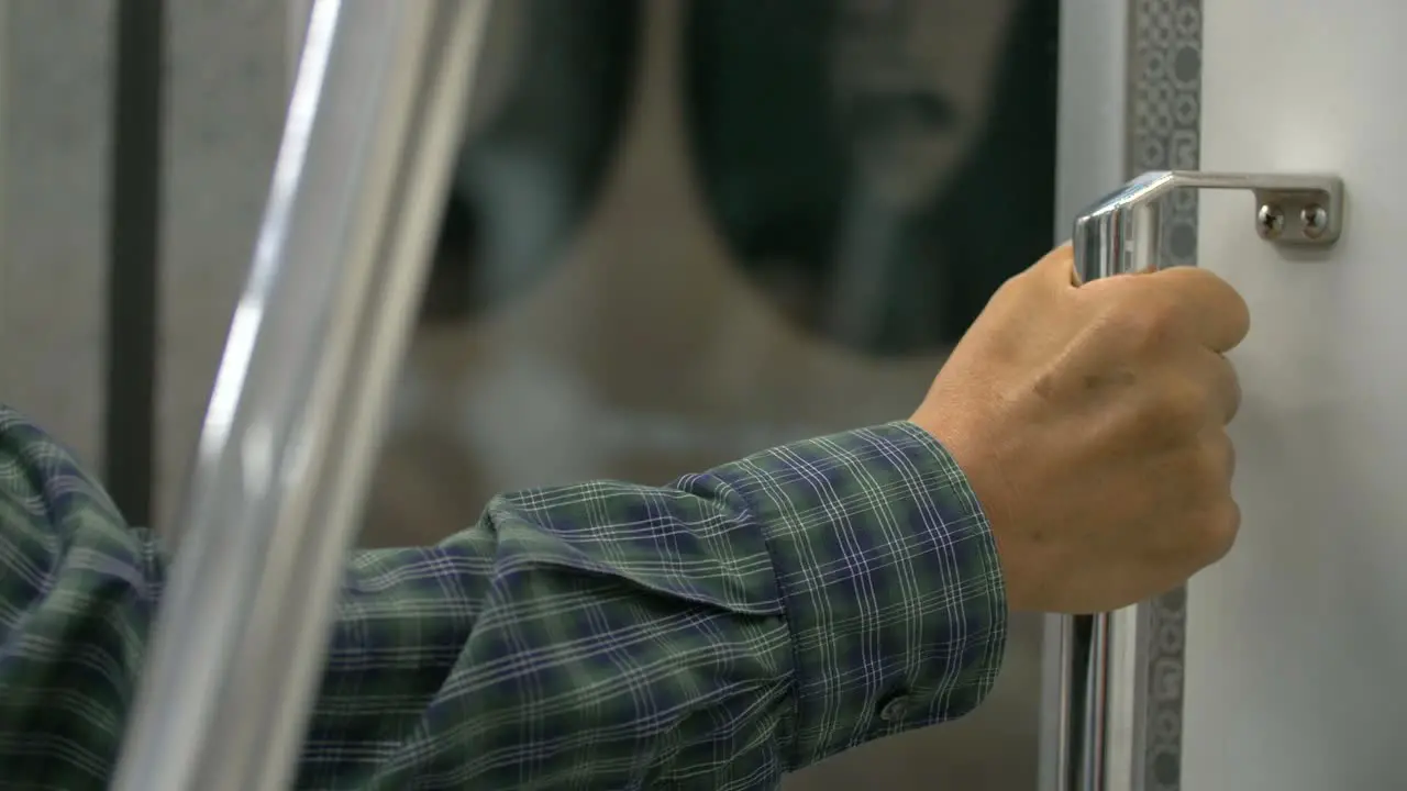 Man Holding Hand Rail on Train