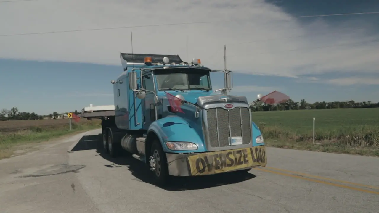 Oversize load truck parked by side of the road with flags