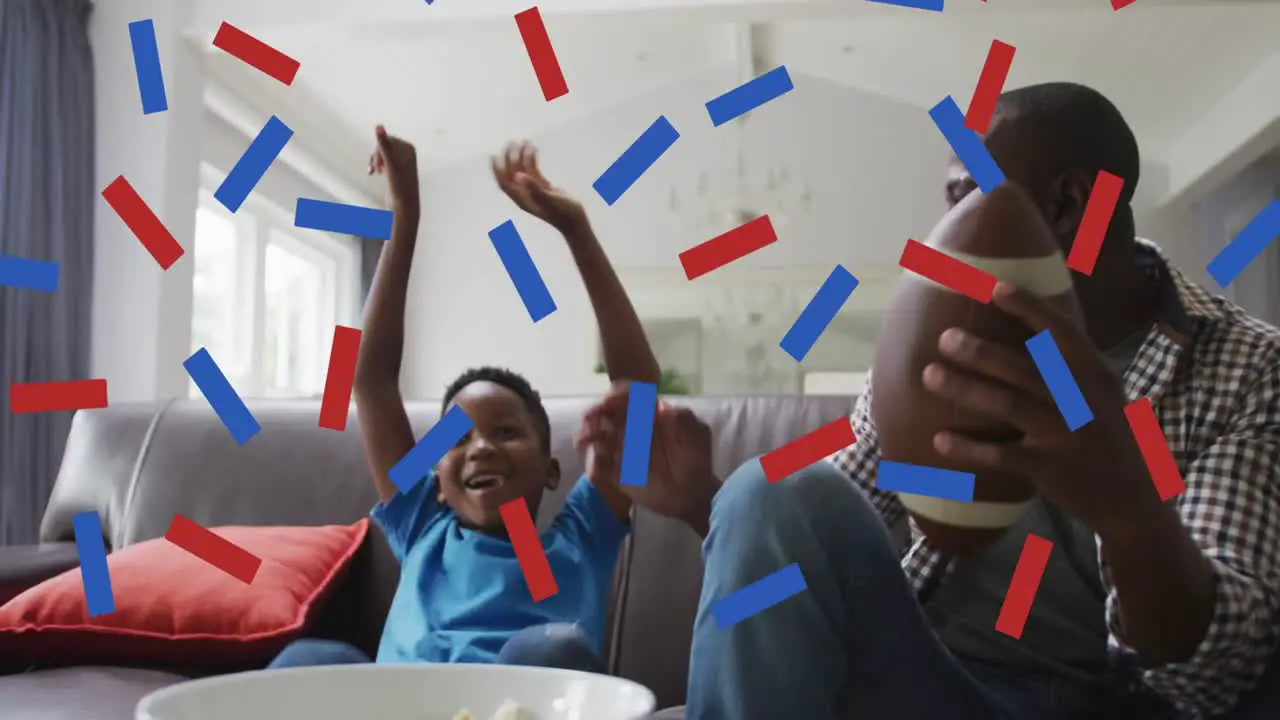 Blue and red confetti falling over african american dad and son cheering while watching sports on tv