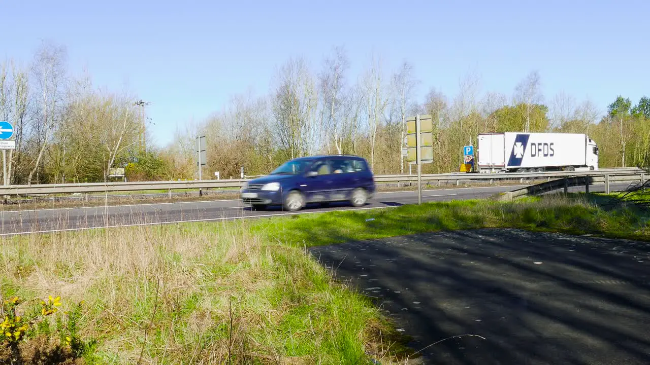 A stationary footage of fast moving trucks and vehicles along the highway