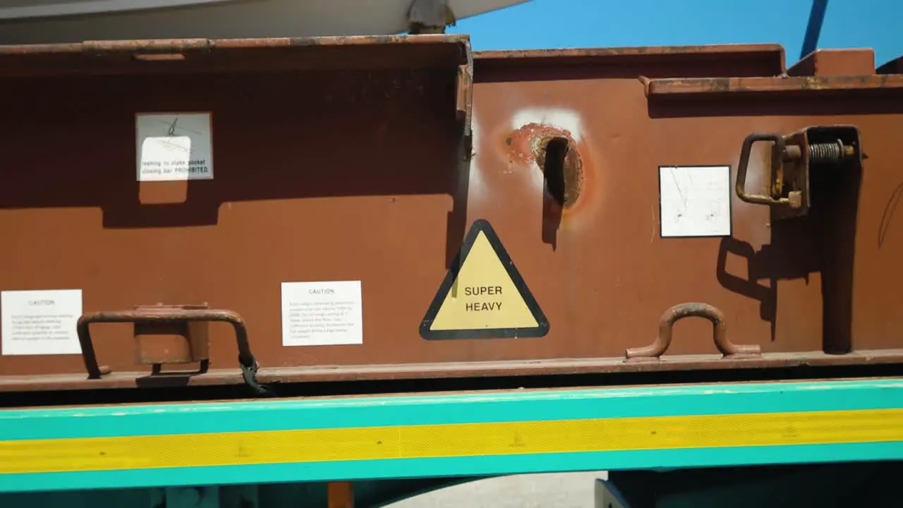 The camera glides from a 'Super Heavy' sign affixed to a truck platform revealing a boat perched atop the sturdy transport