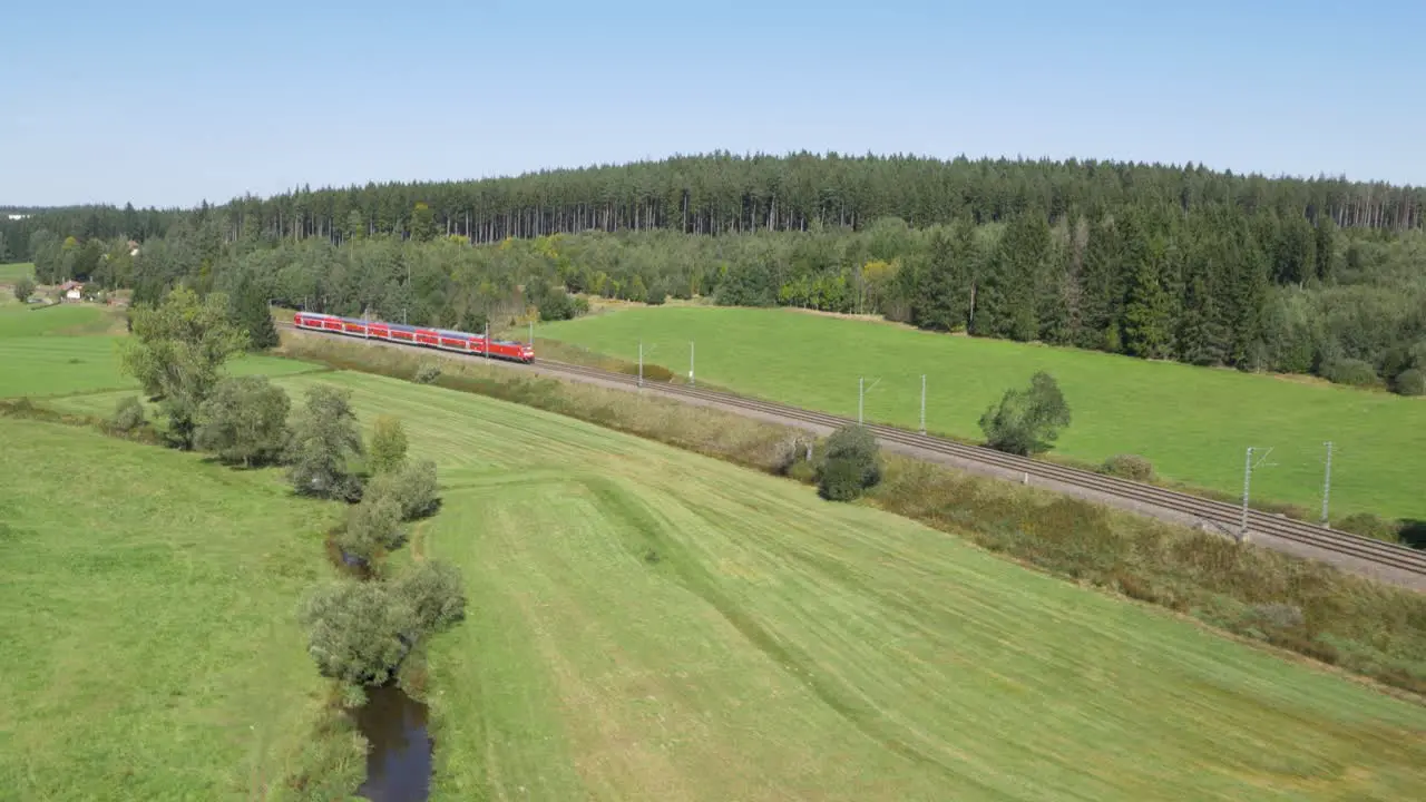 Aerial shot of a red DB train moving through a lush green landscape