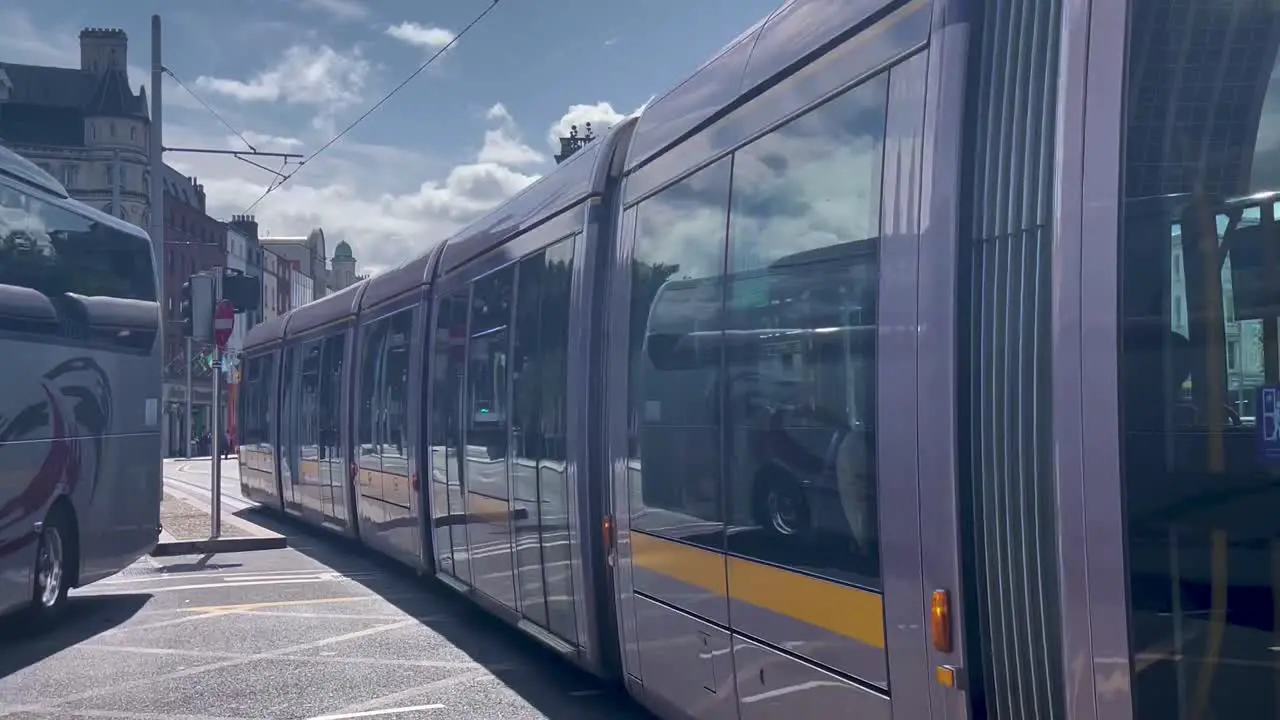 4K of A Luas Tram crossing O'Connell Bridge in Dublin northwards towards O'Connell St as a Bus turns Right on to Eden Quay