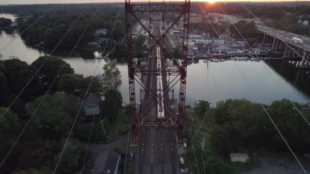 Overhead Drone Shot Pan Down Commuter Train Passing Below at Sunset