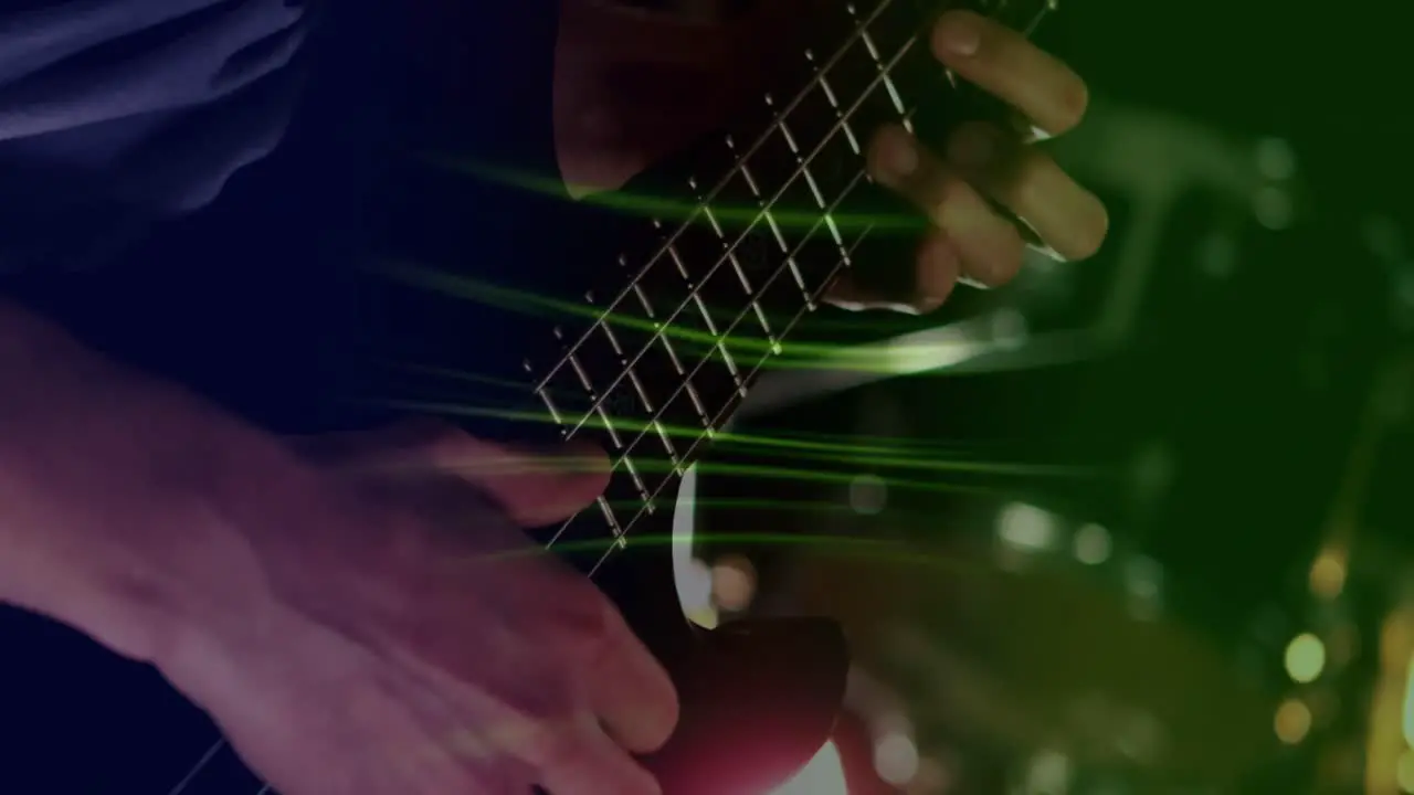 Animation of glowing green light trails over mid section of caucasian man playing guitar