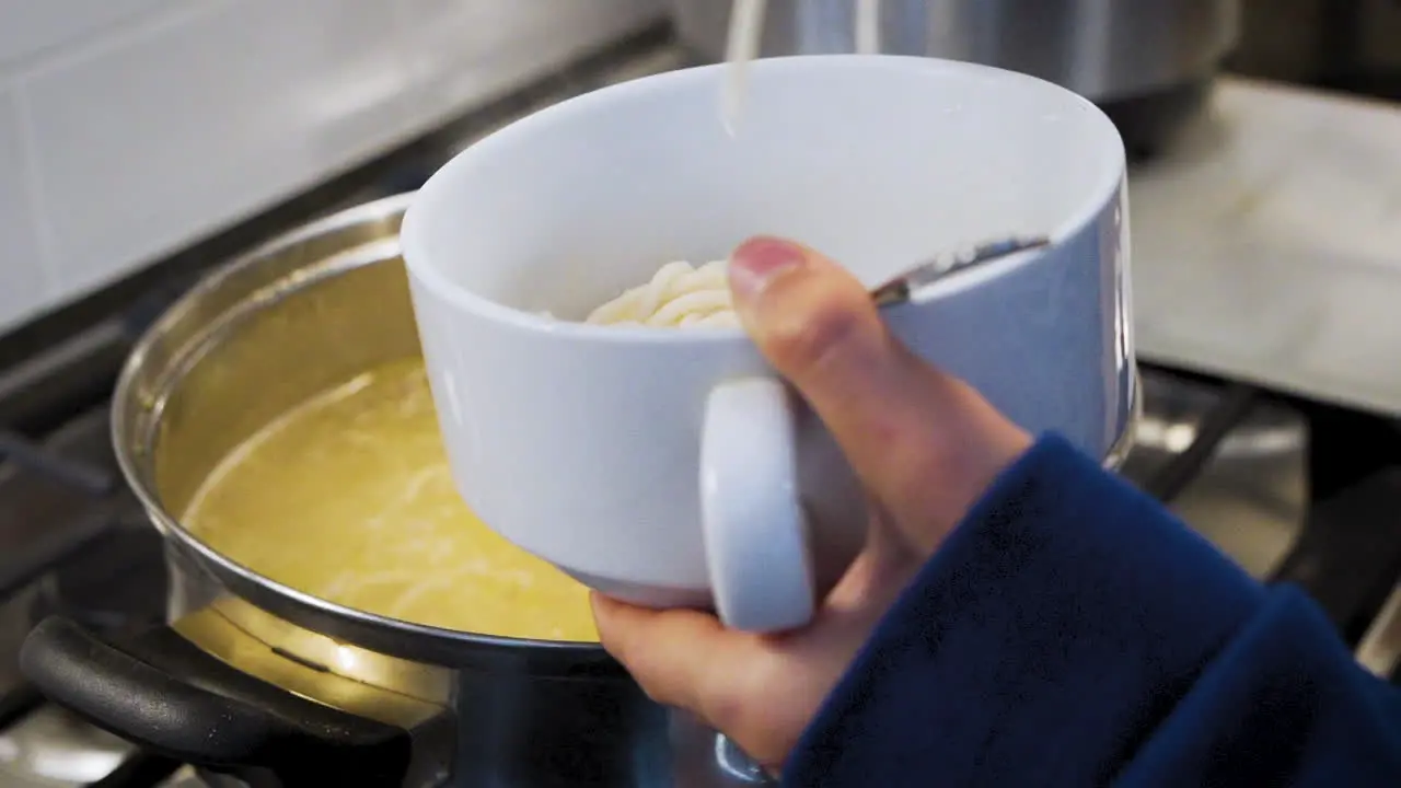 Mom filling up a bowl with spaghetti in the kitchen