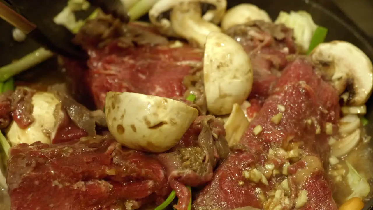 Korean Food Preparation Person Flipping Meat In A Pot Close up shot