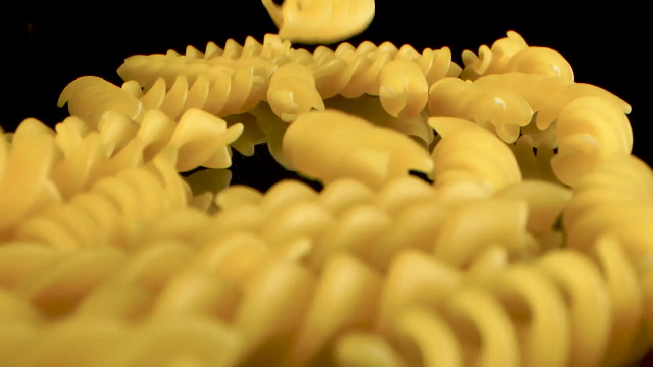 Slow Motion Macro Shot Of Falling fusilli on black mirror surface