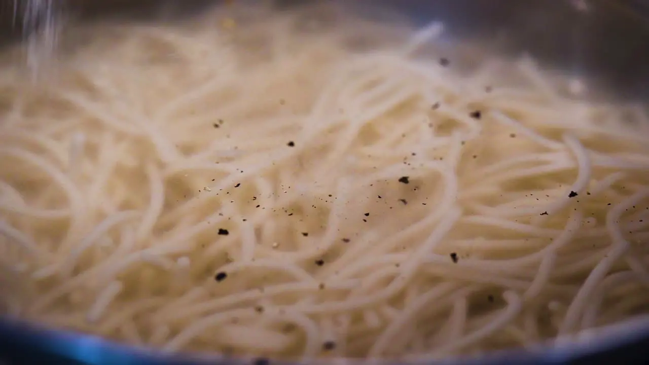 Close up of a chef adding salt to a pot of soup in slow motion