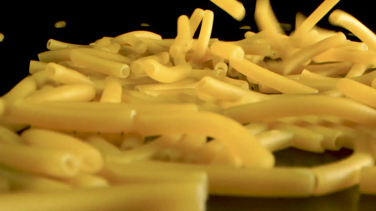 Slow Motion plus Macro Shot Of Falling macaroni on pasta in black table