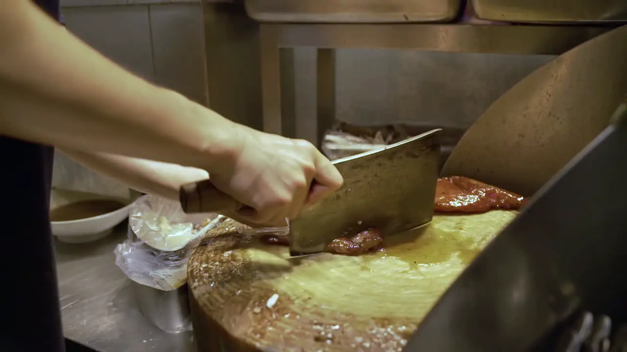 Man Chopping A Slice Of Roasted Meat With A Butcher's Knife In Guangzhou China close up