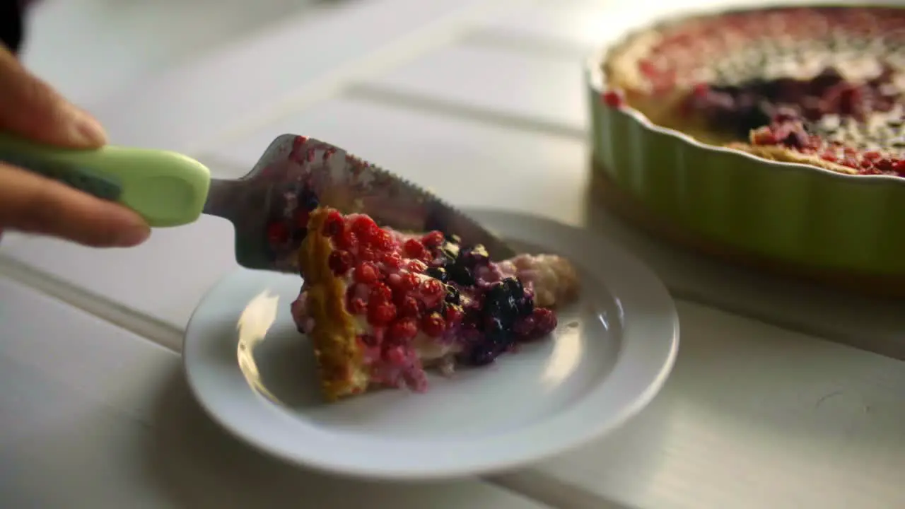 A person slices a piece of dessert and puts it on a plate