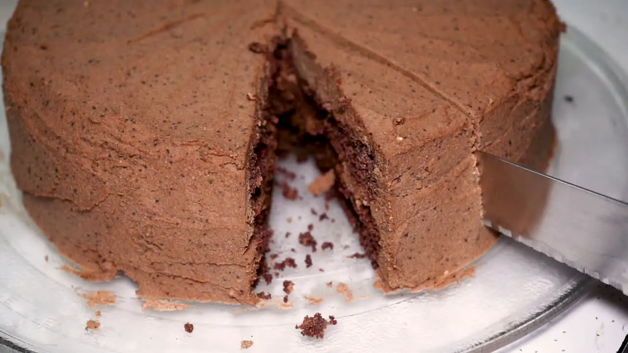 Slow motion cutting a piece of delicious low carb chocolate ketogenic cake with a serrated knife