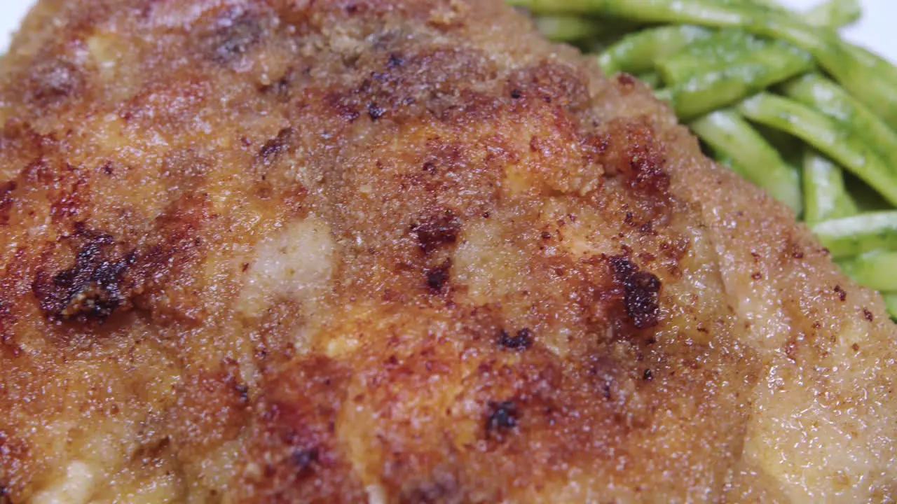 Super close up of fried breaded chicken on green spaghetti