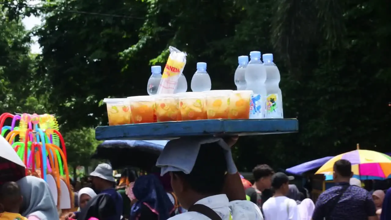 Glass iced tea sellers go around looking for customers during cultural carnival