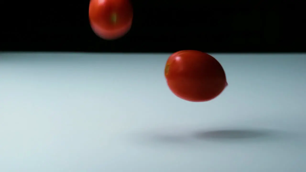 Slow Motion Shot of Tomatoes of Different Colours Falling Bouncing and Rolling onto a White Surface untill they Stop Moving