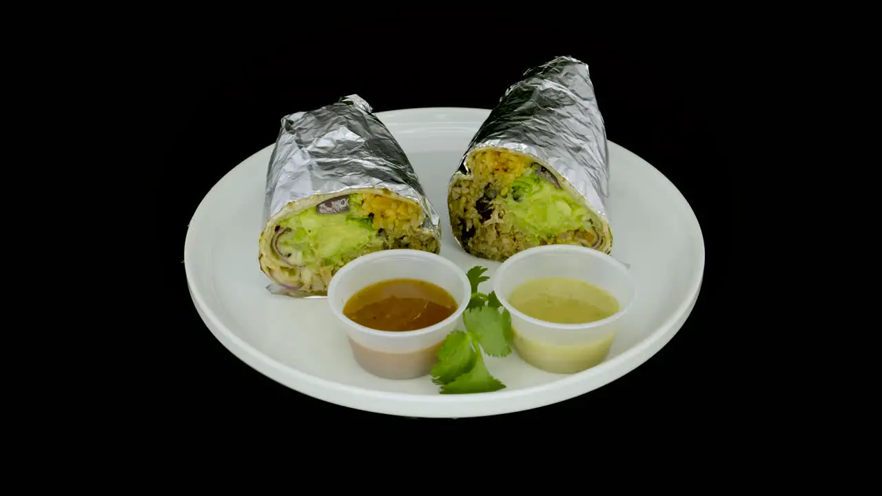 Foil-wrapped burrito on a turntable and sauces