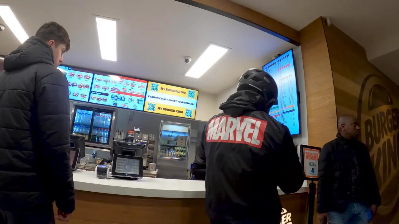 Burger King waitress serves order to a food delivery courier picking up the paper bags Brussels Belgium