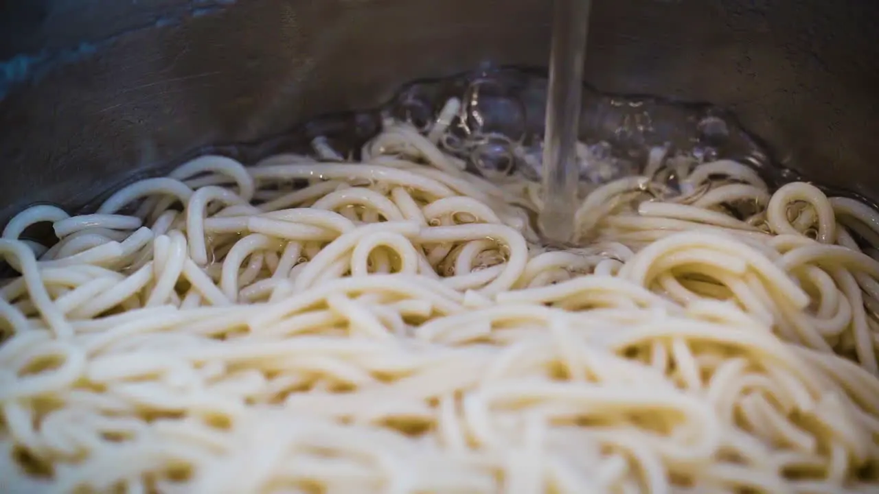 Filling a pot of noodles with water in slow motion