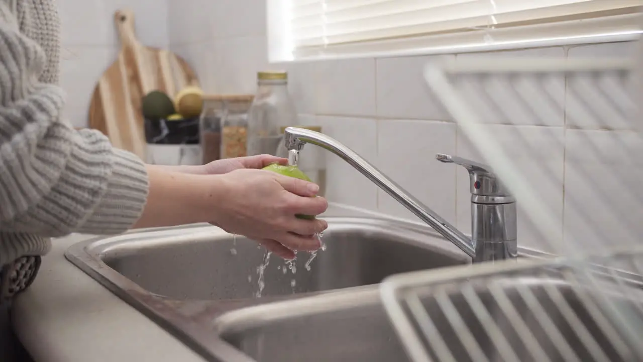 Woman hands washing an apple in the kitchen in slow motion