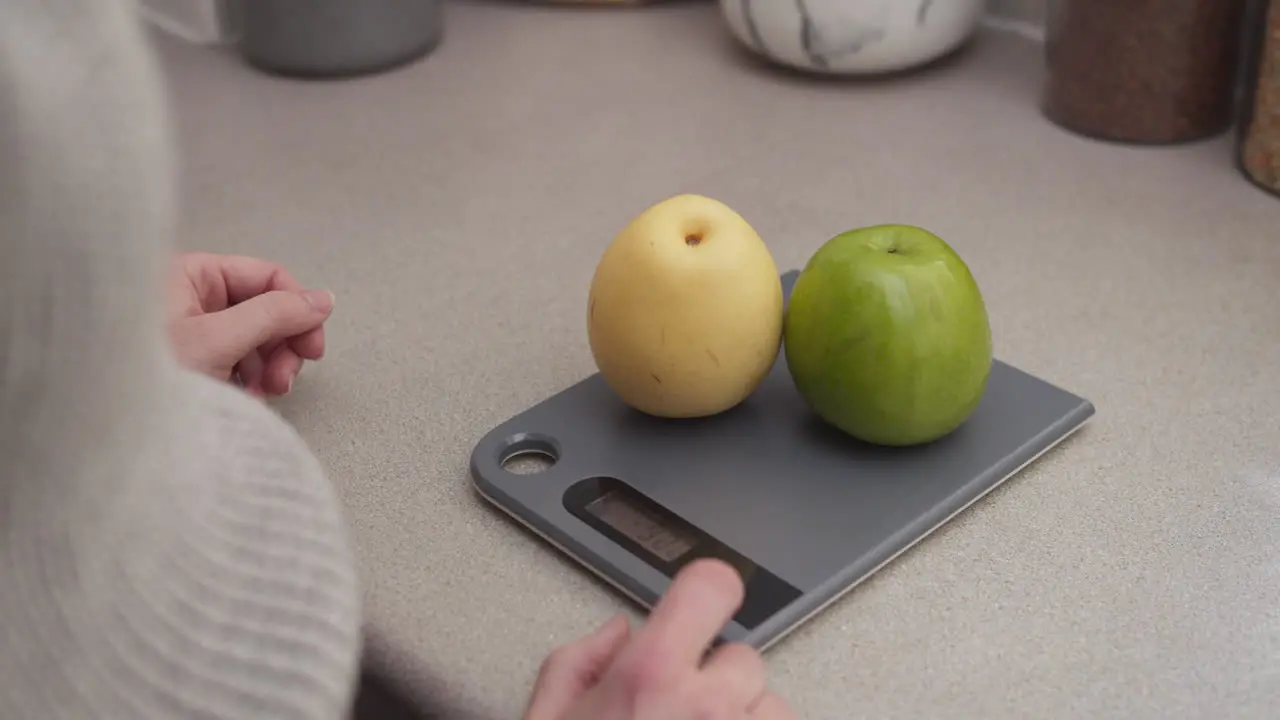 Hands put some fruits on the kitchen scale to weigh Close up shot