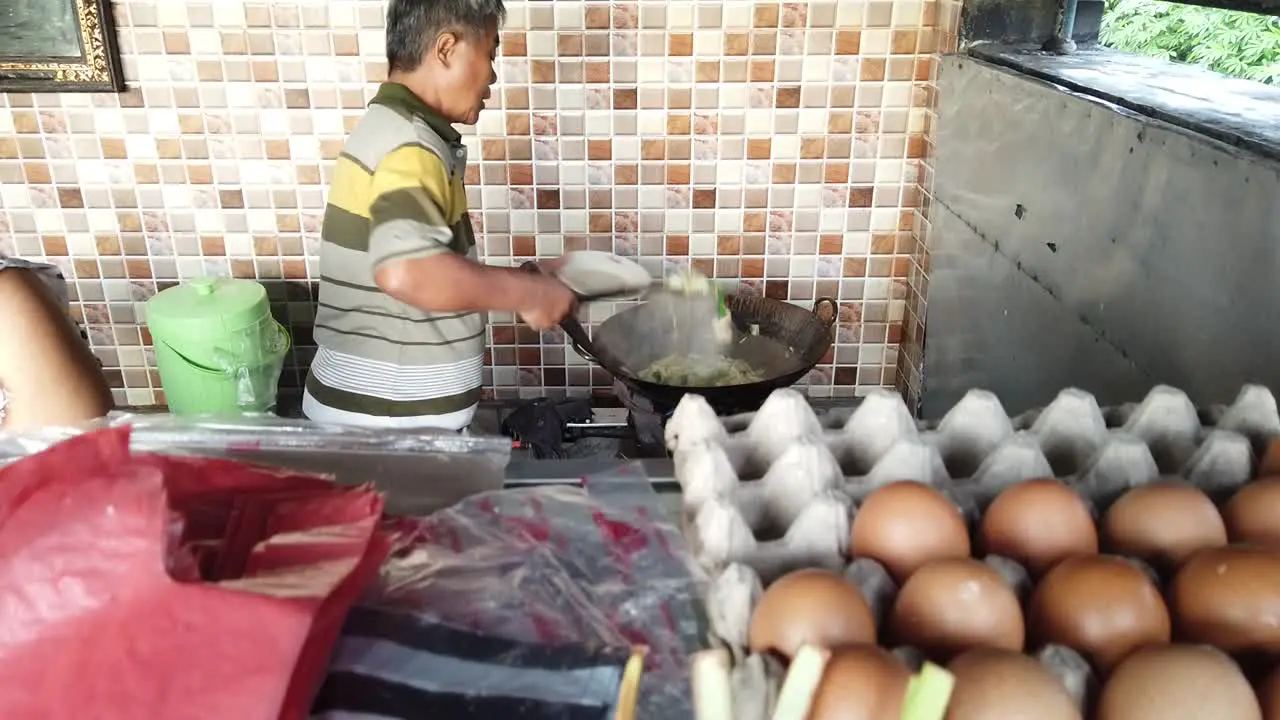 Indonesian Chef Cooking Sauteed vegetables in Bali Cap Cay Local Warung Store a Family Business Husband and Wife among Hindu Religious Offerings