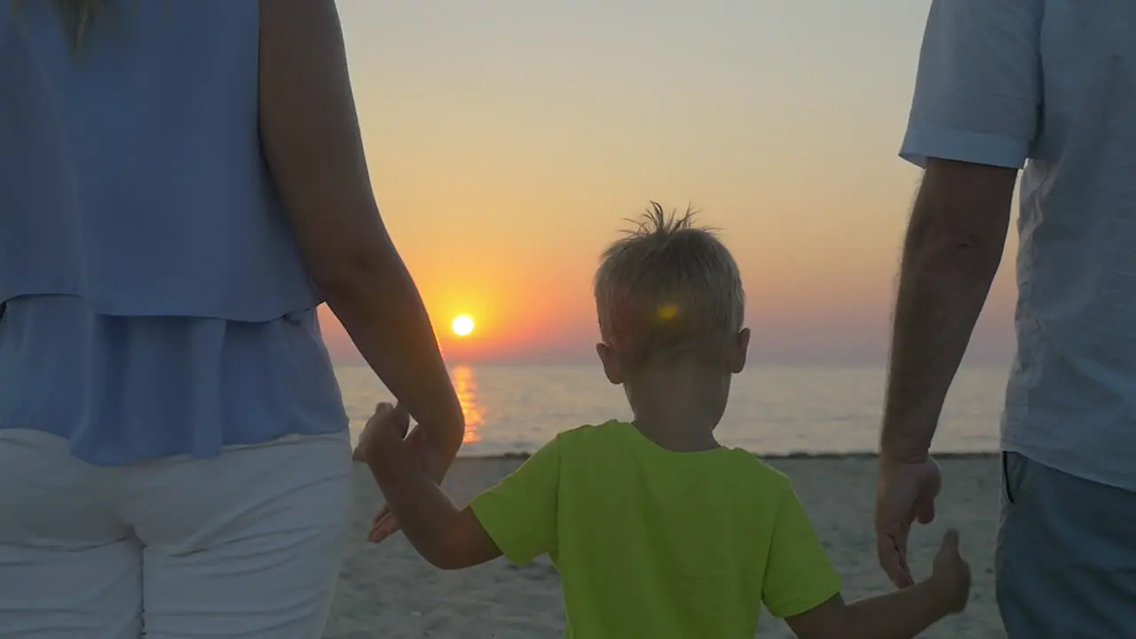 Family with child looking at sunset over sea