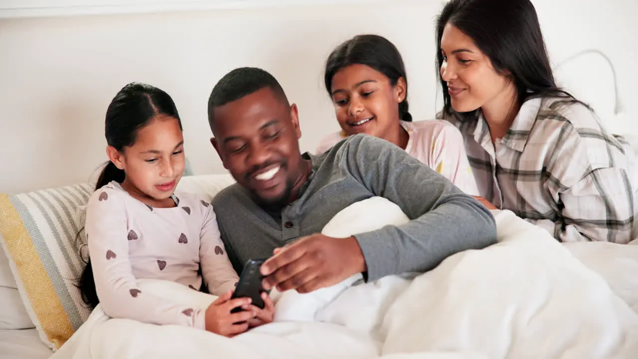 Parents girl children and bed with phone