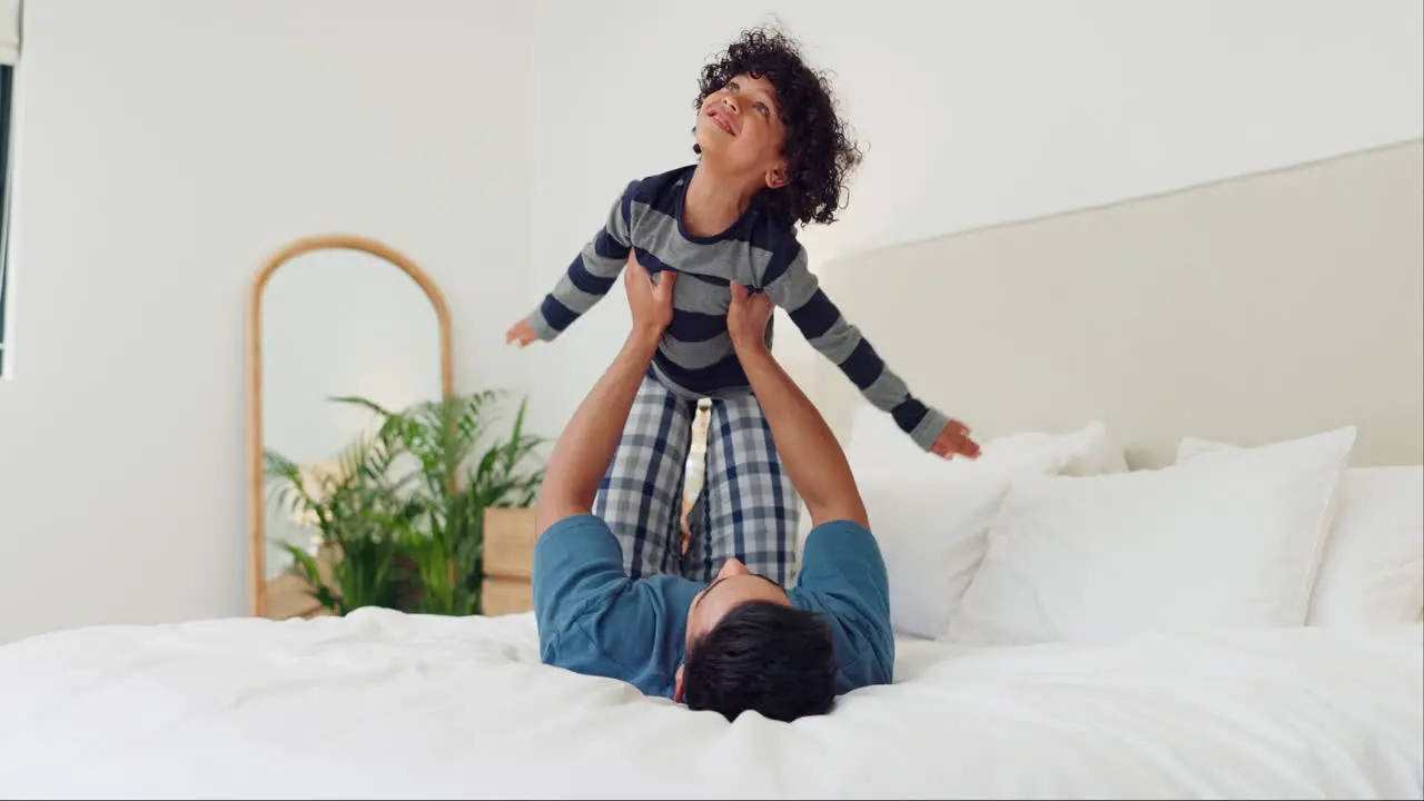 Happy child and father on bed for airplane games