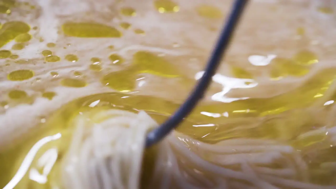 Close up of a chef stirring oil into a pot of soup in slow motion