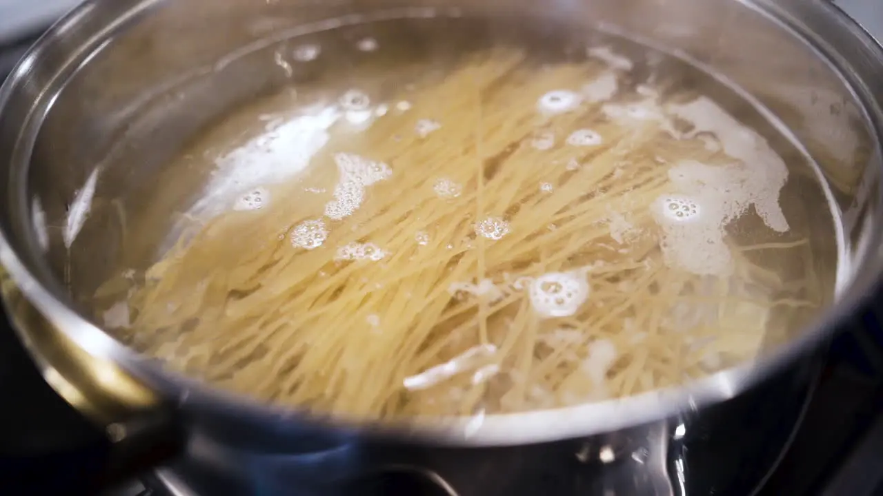 Dropping a handful of spaghetti noodles into a pot of boiling water in slow motion